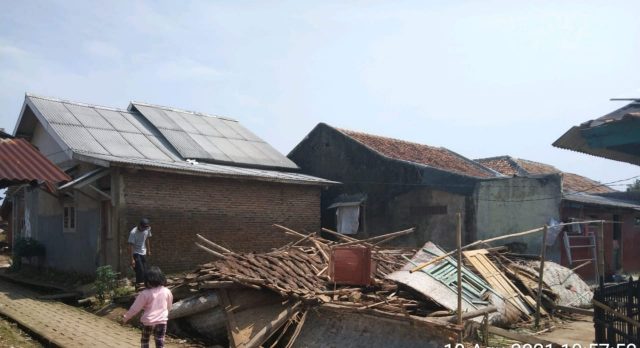 Warga sedang melintas di puing-puing bangunan rumah milik anak yatim piatu yang roboh.