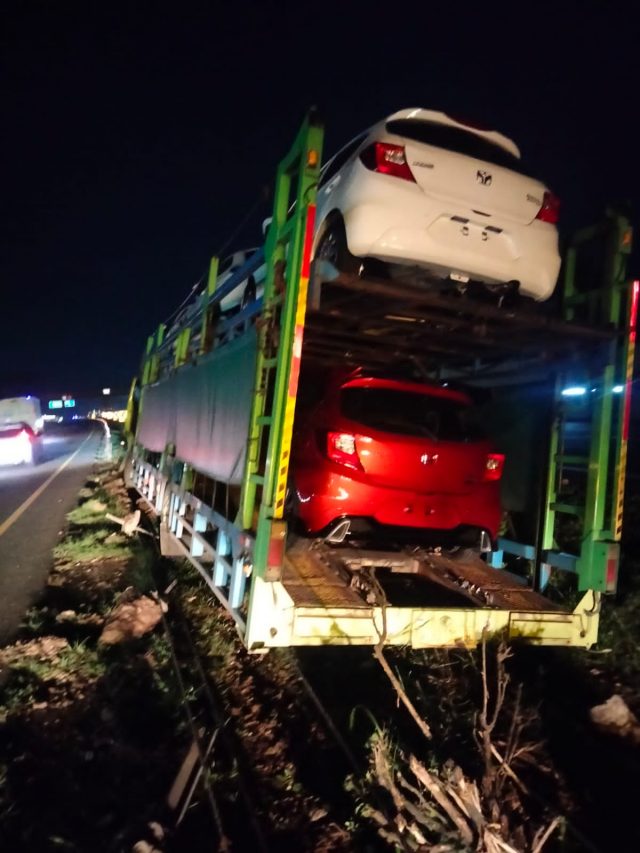 Truck Fuso T-9211-DL yang mengangkut mobil baru terperosok di median jalan Tol Tangerang Merak.